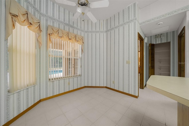 tiled spare room featuring baseboards, ceiling fan, and wallpapered walls