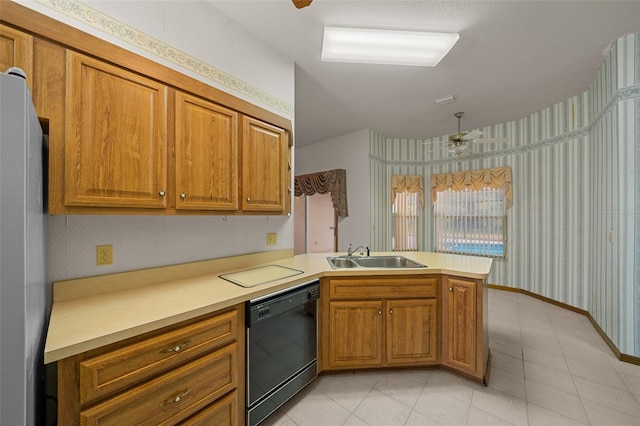 kitchen featuring brown cabinetry, wallpapered walls, a peninsula, a sink, and black dishwasher