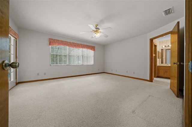 spare room with visible vents, a textured ceiling, baseboards, light colored carpet, and ceiling fan