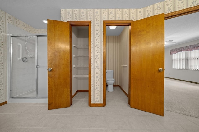 interior space with wallpapered walls, a walk in closet, baseboards, and a closet