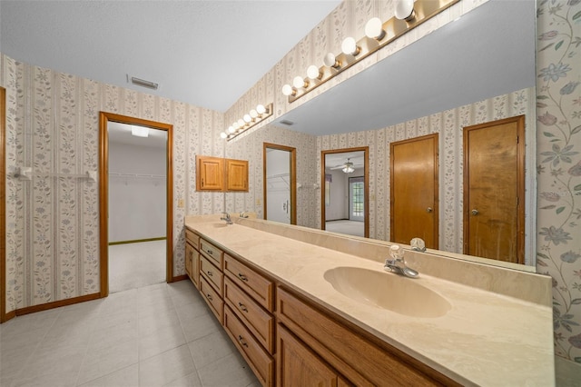 full bath featuring a sink, baseboards, double vanity, and wallpapered walls