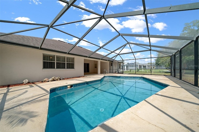 outdoor pool featuring glass enclosure and a patio