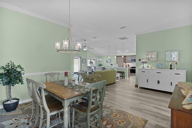 dining area with visible vents, ceiling fan, vaulted ceiling, crown molding, and light wood-type flooring