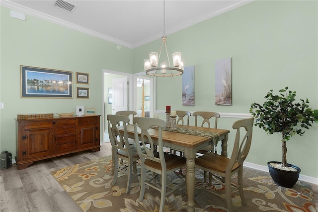 dining area with wood finished floors, baseboards, visible vents, ornamental molding, and a notable chandelier