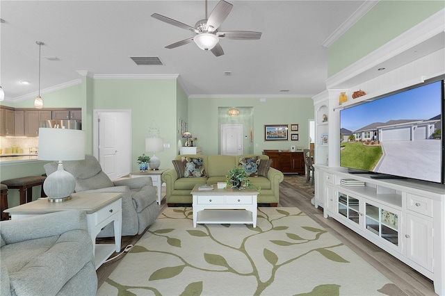 living room featuring ornamental molding, light wood-style floors, visible vents, and ceiling fan