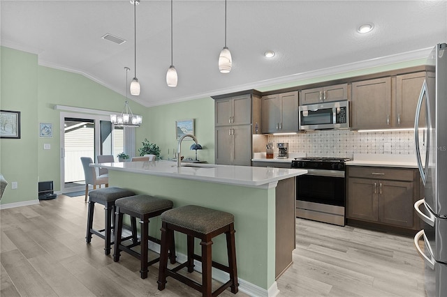 kitchen with a sink, ornamental molding, vaulted ceiling, decorative backsplash, and stainless steel appliances