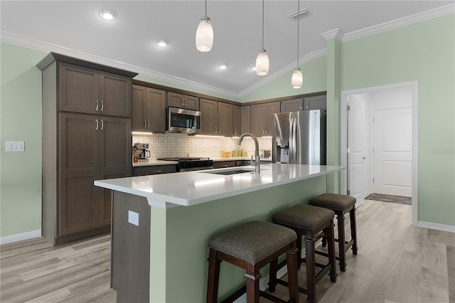 kitchen featuring a sink, a kitchen breakfast bar, tasteful backsplash, appliances with stainless steel finishes, and crown molding