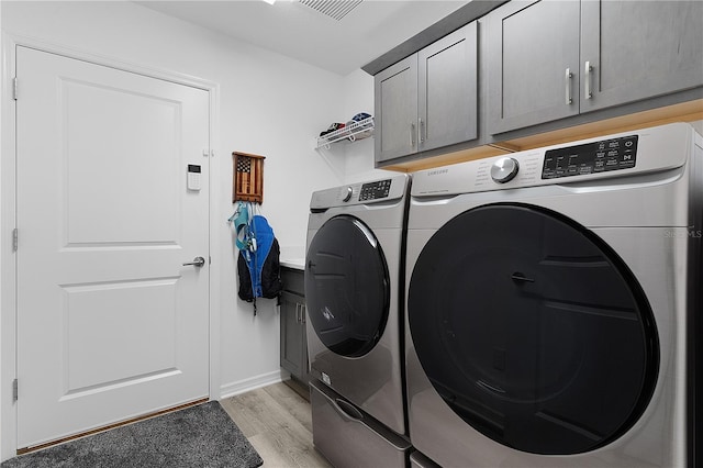 washroom with cabinet space, washer and dryer, and light wood-style flooring