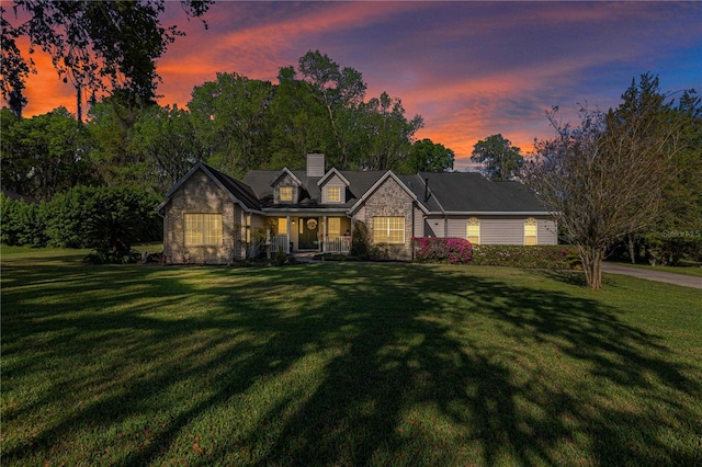 view of front of home featuring a yard, stone siding, and a chimney