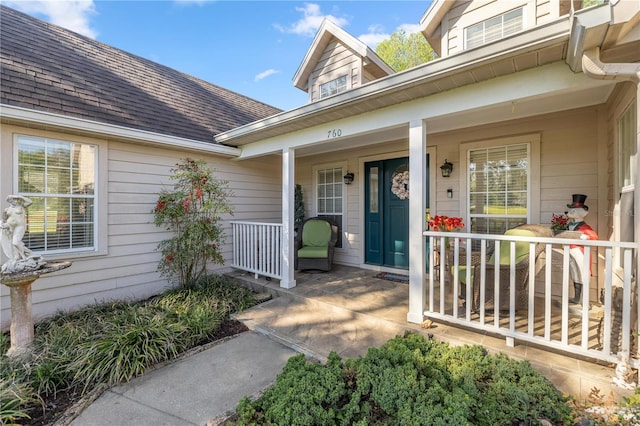 doorway to property featuring roof with shingles and covered porch