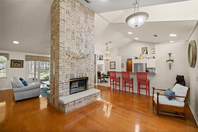 living area featuring a fireplace, wood finished floors, baseboards, and a chandelier