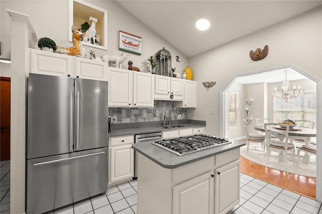 kitchen with a sink, white cabinetry, appliances with stainless steel finishes, light tile patterned floors, and decorative backsplash