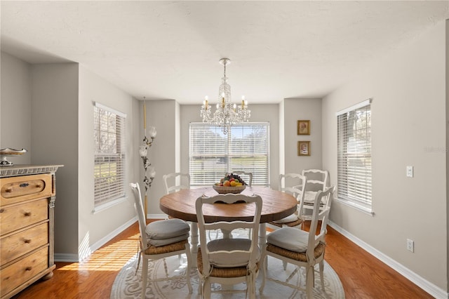 dining area featuring light wood-type flooring, baseboards, and a chandelier