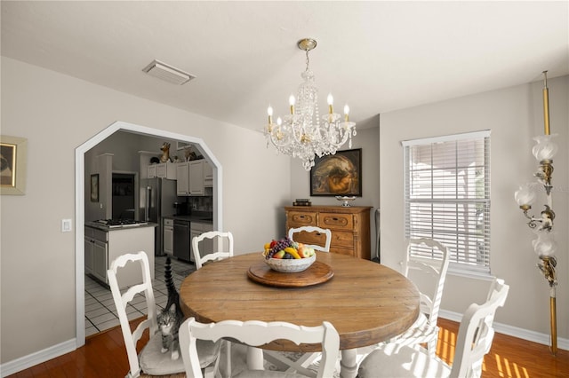 dining area with dark wood finished floors, visible vents, baseboards, and an inviting chandelier