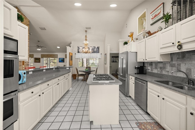 kitchen featuring visible vents, a kitchen island, light tile patterned floors, stainless steel appliances, and a sink