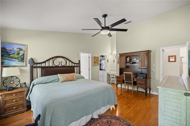 bedroom featuring a ceiling fan, wood finished floors, visible vents, baseboards, and lofted ceiling