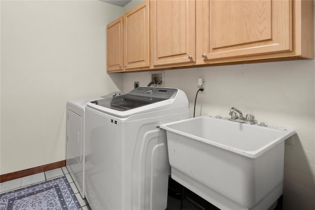 laundry area featuring tile patterned flooring, baseboards, washer and clothes dryer, cabinet space, and a sink