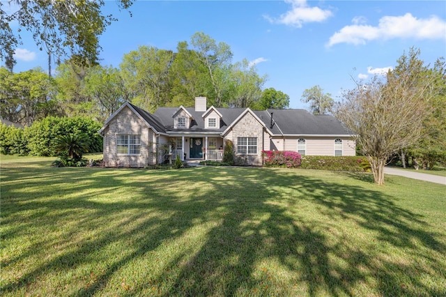 view of front of property with a front yard, covered porch, stone siding, and a chimney