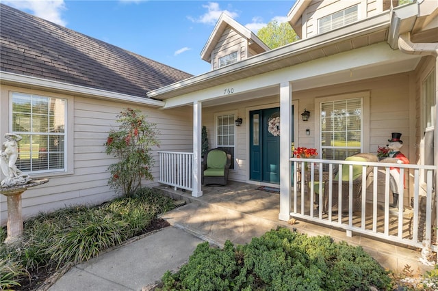 entrance to property featuring a porch and roof with shingles