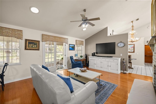 living area with ceiling fan with notable chandelier, high vaulted ceiling, visible vents, light wood finished floors, and baseboards