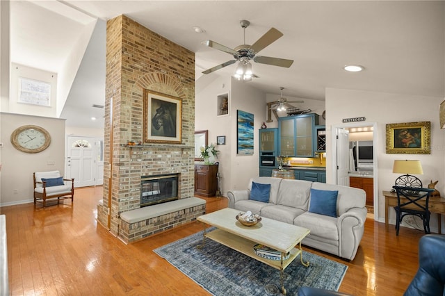 living room featuring baseboards, a fireplace, ceiling fan, high vaulted ceiling, and wood finished floors