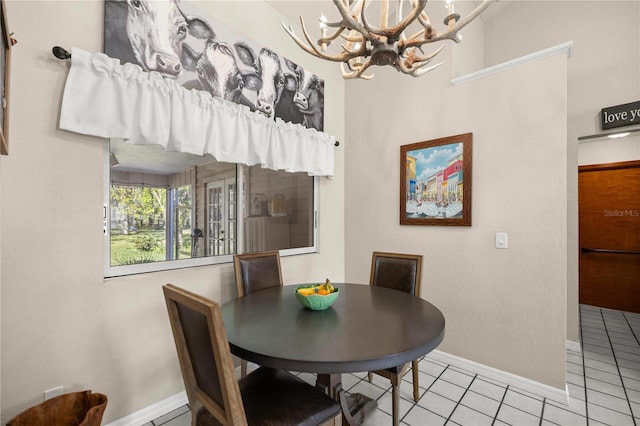 tiled dining space featuring baseboards and a notable chandelier