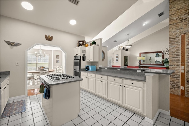kitchen with visible vents, a center island, a notable chandelier, appliances with stainless steel finishes, and vaulted ceiling