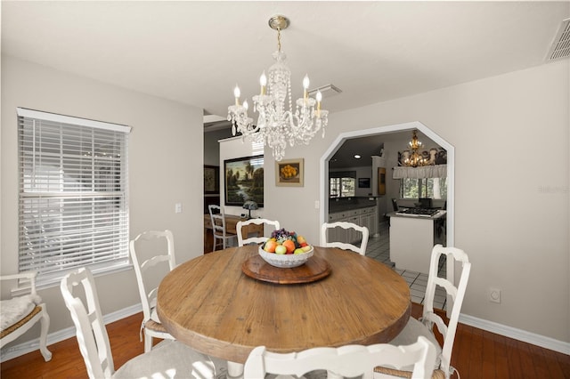dining space featuring a chandelier, wood finished floors, baseboards, and visible vents