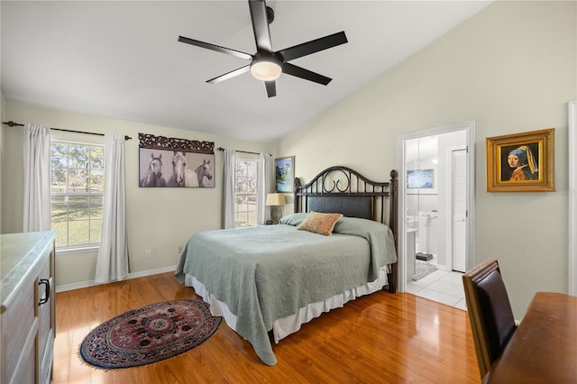 bedroom featuring baseboards, ensuite bathroom, light wood-style floors, ceiling fan, and high vaulted ceiling