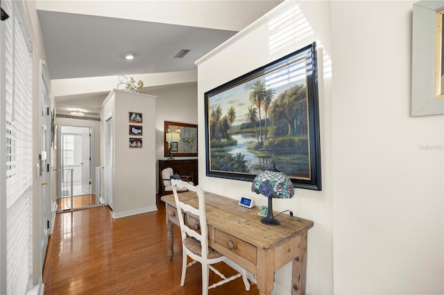 corridor featuring visible vents, baseboards, and wood finished floors
