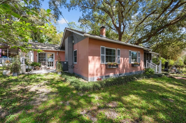 view of side of property featuring concrete block siding, a yard, and a chimney