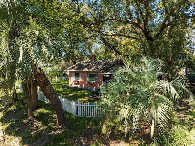 rear view of house featuring a fenced front yard and a chimney