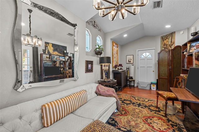 living room featuring wood finished floors, visible vents, an inviting chandelier, lofted ceiling, and a textured ceiling