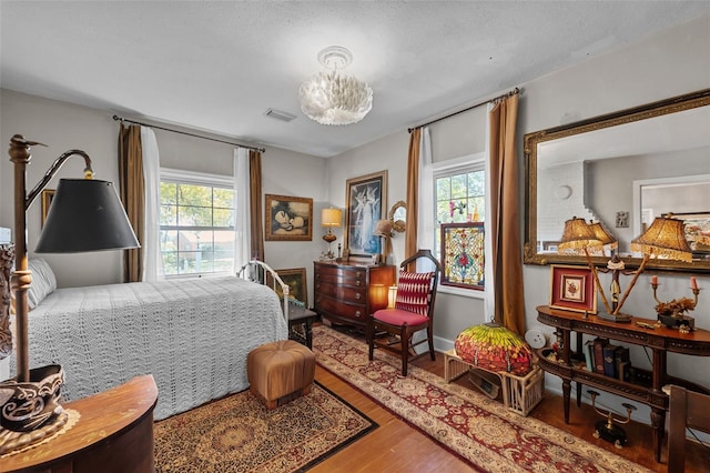 bedroom with multiple windows, wood finished floors, and visible vents