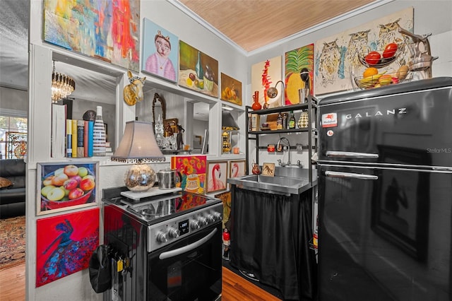 kitchen with ornamental molding, a sink, range with electric stovetop, wood finished floors, and freestanding refrigerator