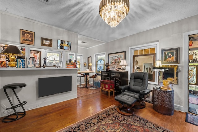 living area with a chandelier, a textured ceiling, baseboards, and wood-type flooring