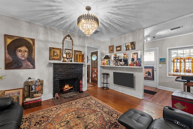 living area featuring visible vents, wood finished floors, a fireplace, and a chandelier