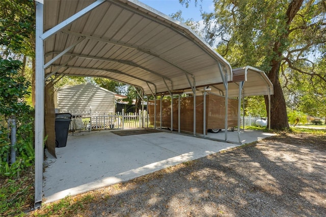 view of parking featuring a detached carport, fence, and driveway