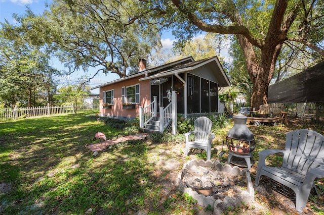 rear view of property featuring fence, a lawn, a chimney, and a sunroom