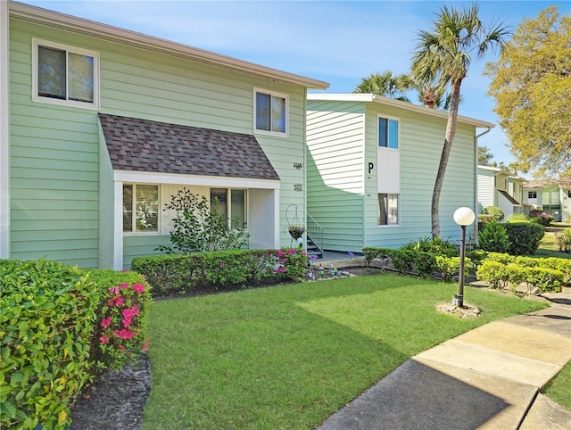 view of front of home featuring a shingled roof and a front yard