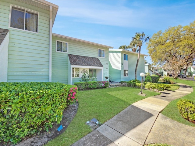 multi unit property featuring roof with shingles and a front lawn