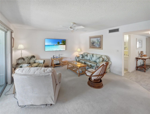 carpeted living room with a textured ceiling, visible vents, and ceiling fan