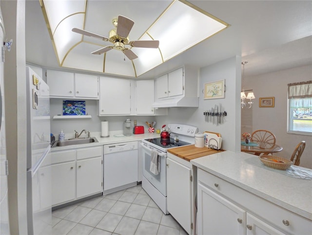 kitchen with under cabinet range hood, ceiling fan with notable chandelier, white cabinets, white appliances, and a sink