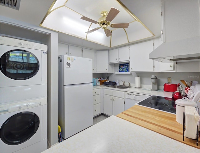 kitchen with white appliances, visible vents, a sink, light countertops, and stacked washer and clothes dryer