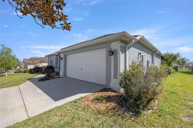 view of side of property with stucco siding, an attached garage, concrete driveway, and a yard