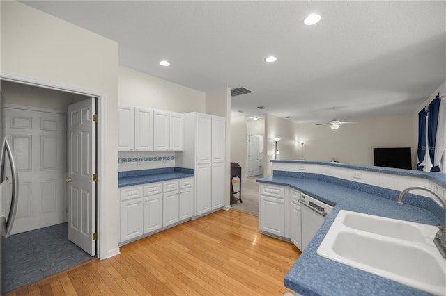 kitchen featuring visible vents, dishwasher, light wood-style flooring, white cabinets, and a sink