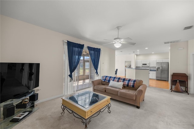 living area featuring visible vents, light colored carpet, and ceiling fan