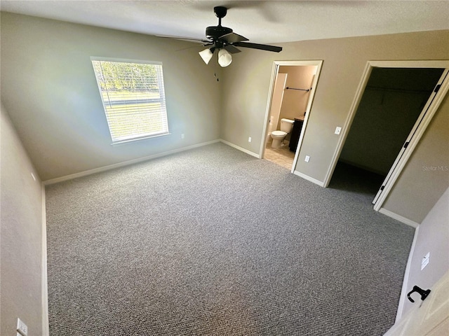 unfurnished bedroom with carpet, baseboards, a spacious closet, a closet, and connected bathroom