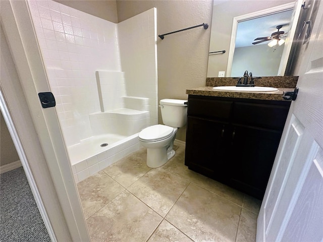 full bath with vanity, baseboards, tiled shower, tile patterned flooring, and toilet