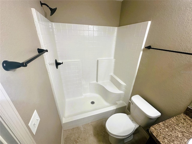 bathroom with tile patterned floors, toilet, a shower, and a textured wall